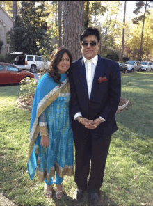 a man in a suit and a woman in a blue and gold dress pose for a picture