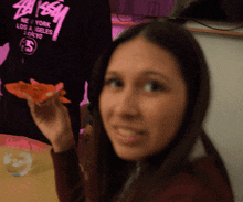 a woman is holding a piece of pizza in front of a black shirt that says new york los angeles tokyo