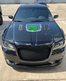 a black car with a green box in the hood is parked in a parking lot