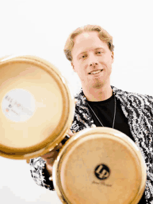 a man in a sequined jacket holds two lp drums in his hands