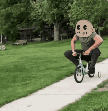 a man is riding a tricycle with a cartoon face on his head