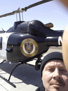 a man stands in front of a black and white helicopter that says we make a difference