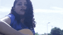 a young woman in a blue shirt is playing a guitar .