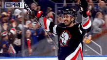 a hockey player celebrates with his arms in the air in front of a crowd and a scoreboard that says stl 2