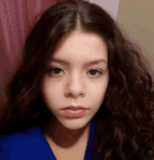 a young girl with curly hair is wearing a blue sweater