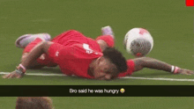 a soccer player is laying on the field with a soccer ball in his hand .