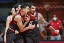 a basketball player with the number 15 on his jersey celebrates with his teammates