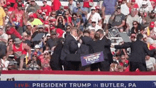 a man is holding a trump sign in front of a crowd of people at a rally .