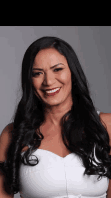 a woman with long black hair and a white top smiles for the camera