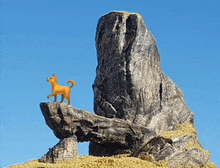 a toy dog standing on top of a rock