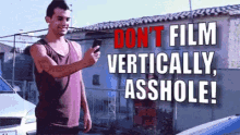 a man is taking a picture of himself with the words " do n't film vertically asshole " behind him