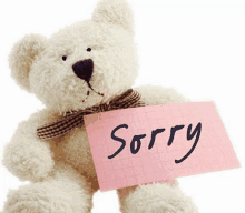 a teddy bear is holding a pink piece of paper that says `` sorry '' .