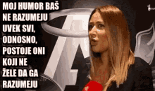 a woman is talking into a microphone in front of a sign that says moj humor bas ne razumeju .