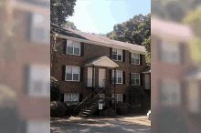 a brick apartment building with stairs leading up to the first floor