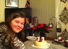 a girl sitting in front of a cake with a number 12 on it