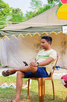 a man sits in a chair with his legs crossed wearing a shirt that says ' green field ' on it