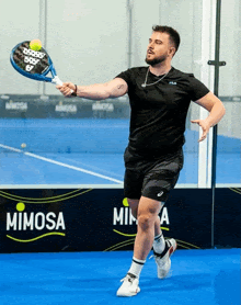 a man is playing tennis in front of a mimosa advertisement