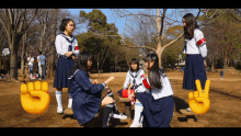 a group of girls in school uniforms are sitting on a bench in a park with a peace sign in the background