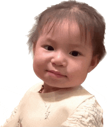 a baby girl wearing a white dress with a floral pattern on it looks at the camera