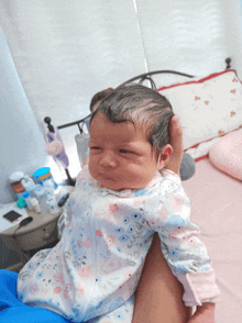 a baby in a floral outfit is being held by someone