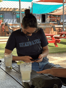 a woman wearing a headwaters t-shirt sits at a table