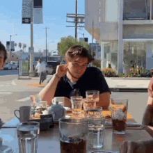 a man sits at a table with glasses of water and a sign that says ' abercrombie & fitch ' on it