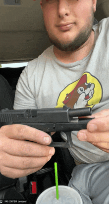 a man holding a gun next to a cup that says leopard