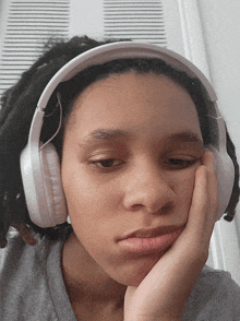 a young girl wearing headphones with her hand on her face