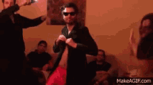 a man in a suit and sunglasses is dancing in a room .