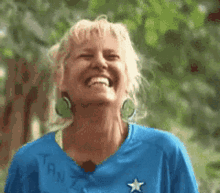 a woman wearing a blue shirt that says tan is smiling