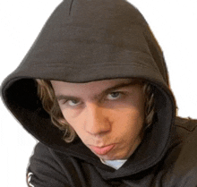 a young man wearing a hooded sweatshirt is making a funny face .