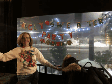 a woman stands in front of a ugly sweater party sign