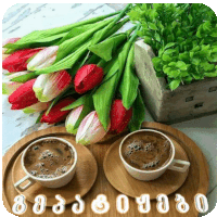 two cups of coffee on a wooden tray next to a bouquet of tulips