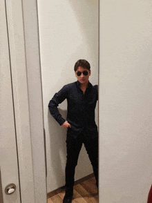 a man wearing sunglasses stands in front of a large mirror