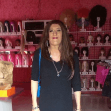 a woman stands in front of a display of wigs