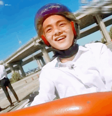 a young man wearing a helmet is smiling while riding a roller coaster .