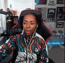 a woman is sitting in a chair in front of a microphone with a sign on the wall that says she shed