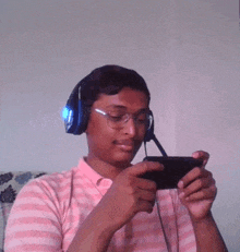 a man wearing headphones and glasses is looking at a cell phone