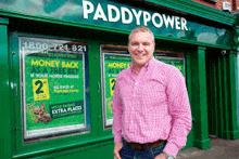 a man in a pink shirt stands in front of a paddypower store