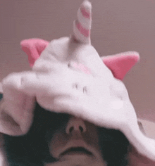 a person is wearing a unicorn hat with pink ears .