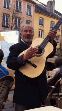 a man with a beard is holding a guitar in front of a building that has a map on it