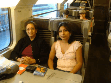 two women sit at a table on a train with a book on the table that says ' butterfly ' on it