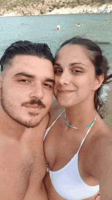 a man and woman are posing for a picture on the beach