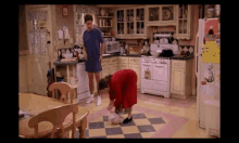 a man and a woman in a kitchen with a sign on the refrigerator that says ' i love you '