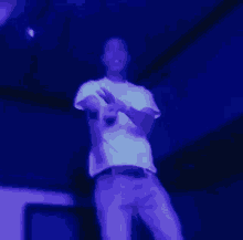 a man in a white shirt and purple pants is standing in a dark room .