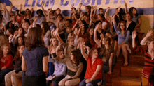 a crowd of people are raising their hands in front of a lion county sign