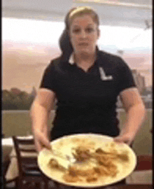 a woman in a black shirt is holding a plate of food in her hands .