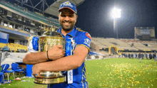 a man in a blue shirt is holding a trophy in his hands .