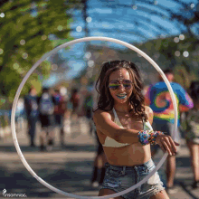 a woman wearing a bikini top and shorts is holding a hula hoop in front of a sign that says insomniac