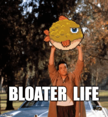 a man is holding a pixelated fish over his head and the caption reads bloater life